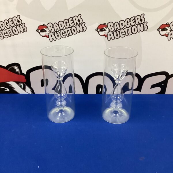 Two clear glass candle holders with elegant design.