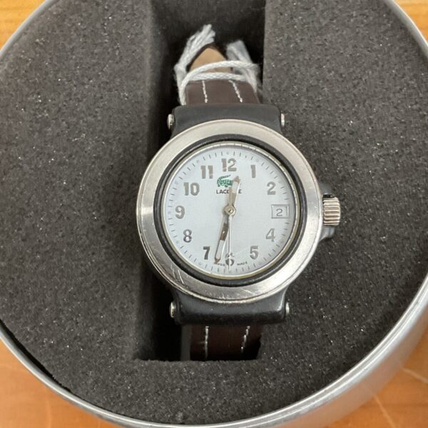 Lacoste watch in original packaging, analogue face, black strap.