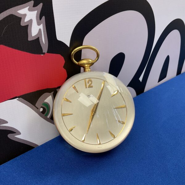 Side view of vintage Imhof ball clock against colourful backdrop.