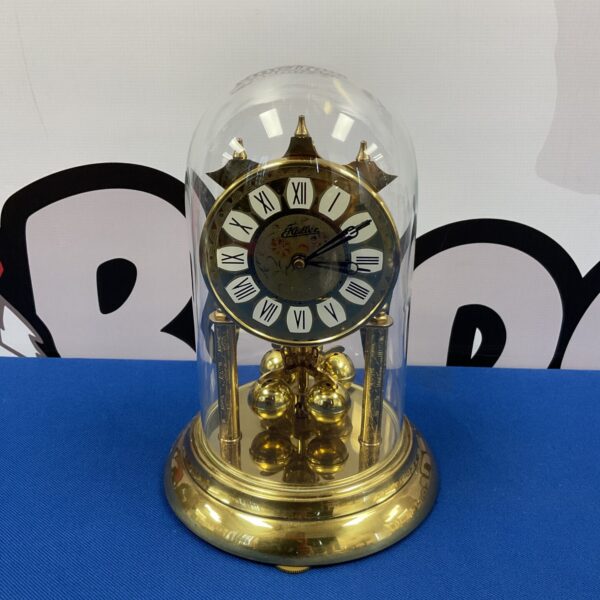 Antique Haller torsion clock with glass dome on display.
