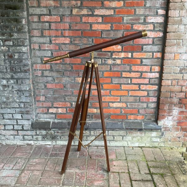 Antique brass telescope on wooden tripod, vintage nautical instrument.