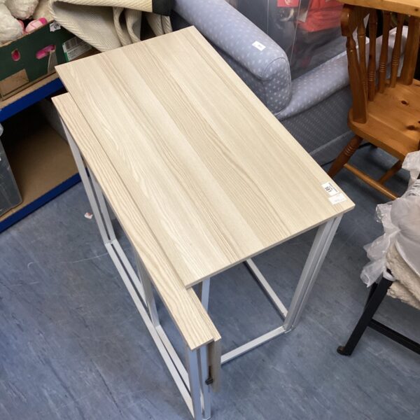 Two light-coloured folding desks stacked together.