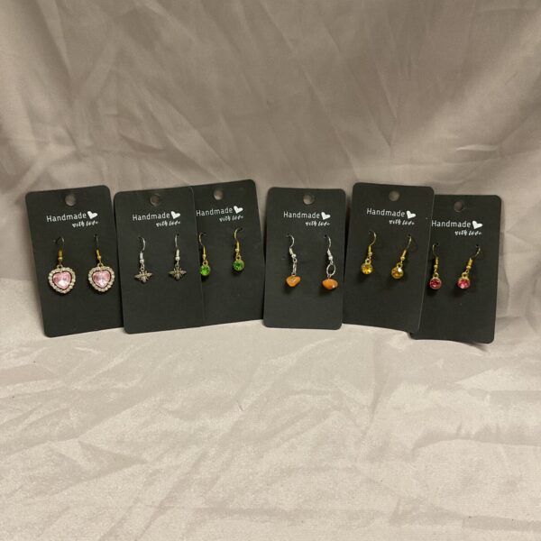 Lot of six pairs of handmade earrings on display.