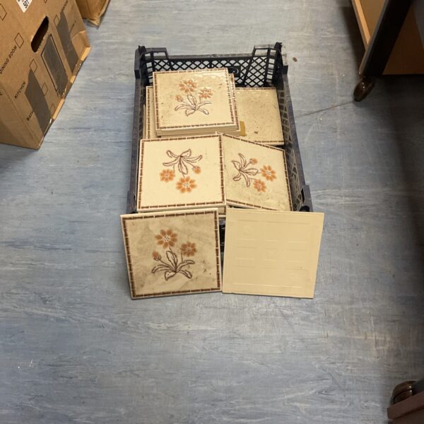 Crate of vintage flower pattern ceramic tiles for restoration.