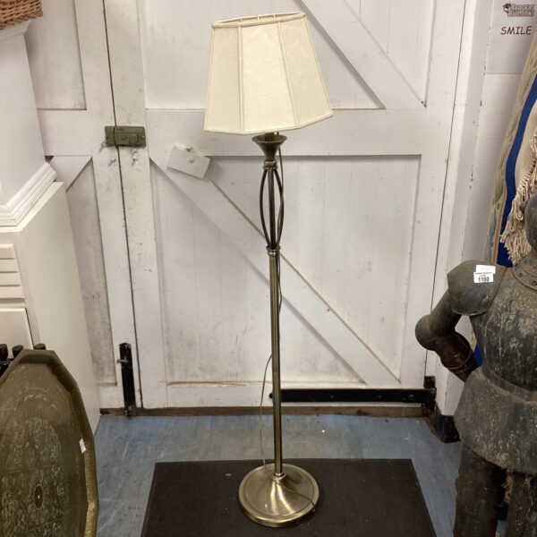 Vintage brass standard lamp with cream lampshade in a room.