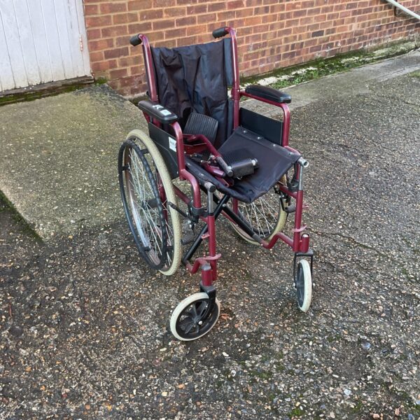 Red Pro Rider folding wheelchair with footrests and push handles.