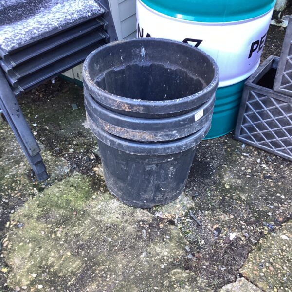 Lot of four dark plastic garden planters for outdoor use.