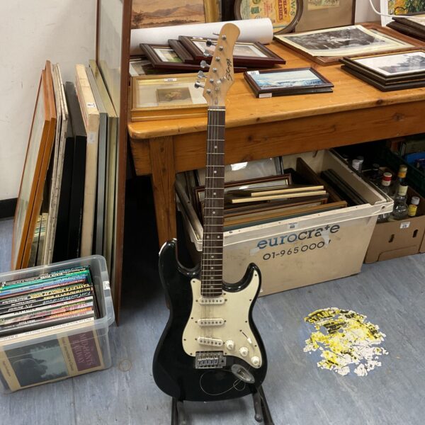 Black Stagg electric guitar displayed on a stand.