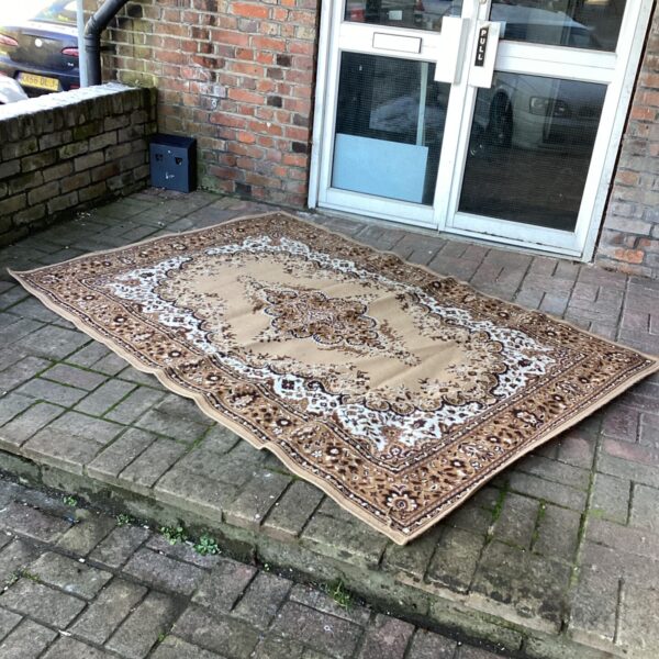 Vintage brown and cream patterned rug on a paved surface.