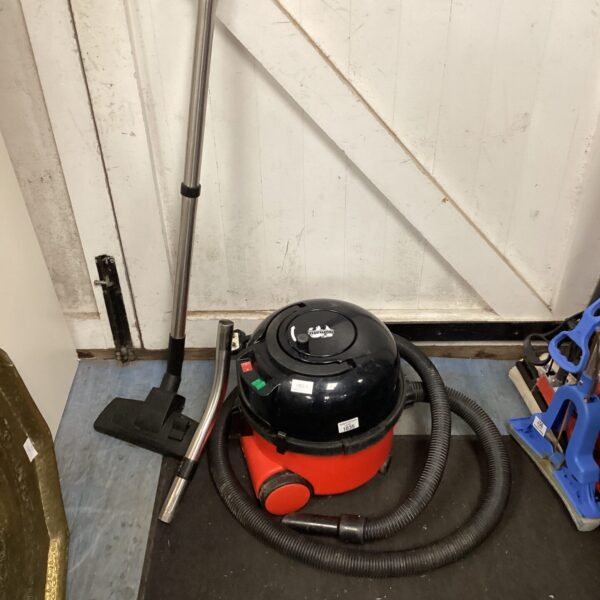 Red Numatic Henry vacuum cleaner with hose and attachments.