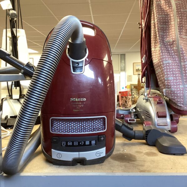 Red Miele C3 canister vacuum cleaner with hose attached.