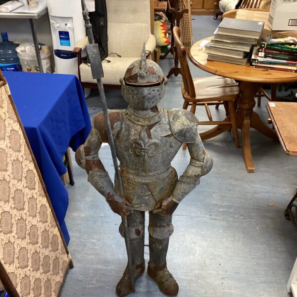 Vintage metal knight armour statue with spear, medieval decor.