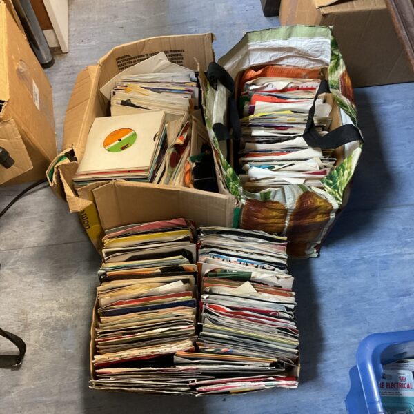 Large collection of vintage 7-inch vinyl records in a box.