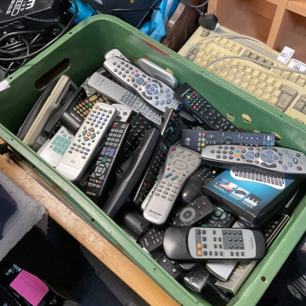 Tray of assorted remote controls for TVs and electronics.