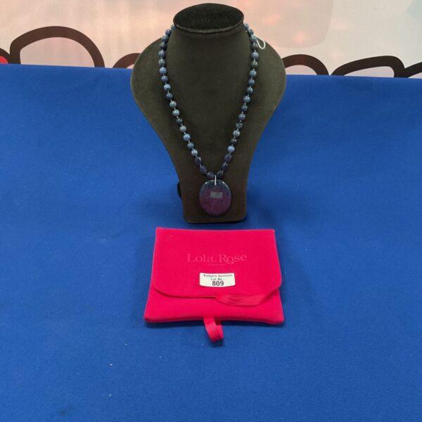 Close-up of a Lola Rose London blue bead necklace with pendant.