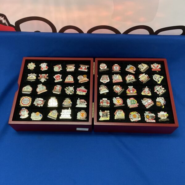 Manchester United pin badges displayed in a case, football collectibles.