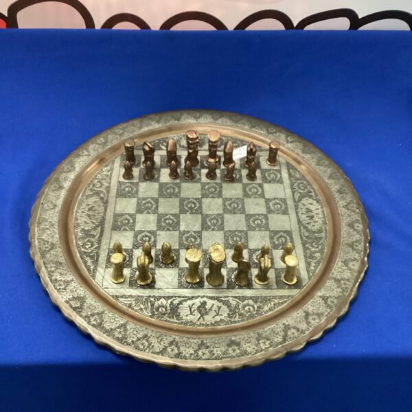 Vintage metal chess set with embossed circular board and pieces.