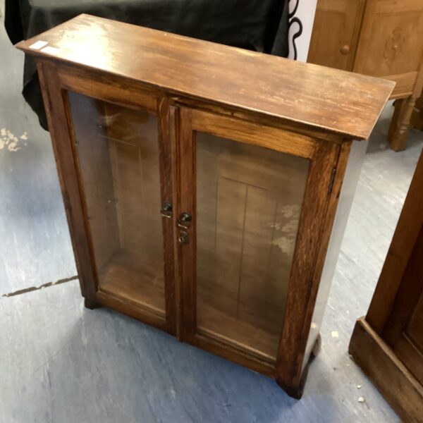 Vintage oak display cabinet with glass door for collectibles.