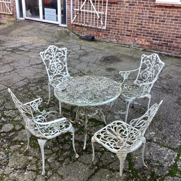 Ornate metal garden set with floral detailing in a garden setting.