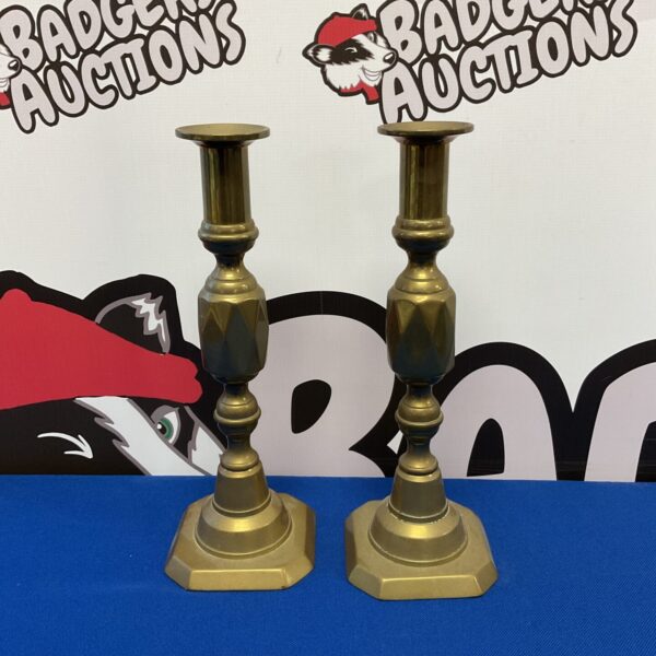 Pair of vintage brass candlesticks on a dark surface.