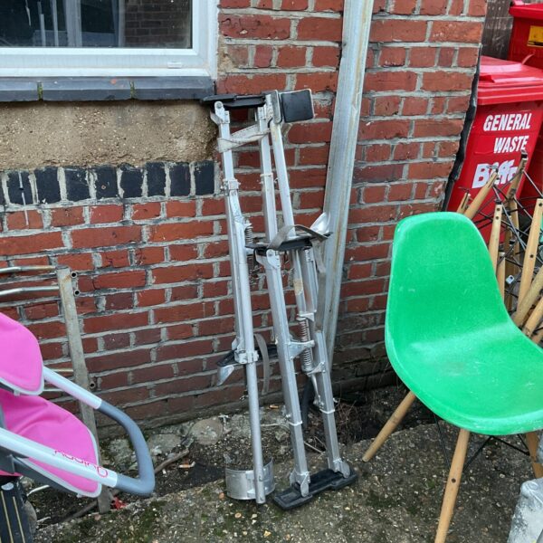Pair of adjustable metal plasterers stilts for construction work.