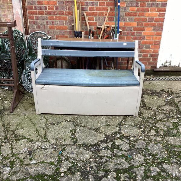 Weathered plastic garden storage bench with lift-up seat.