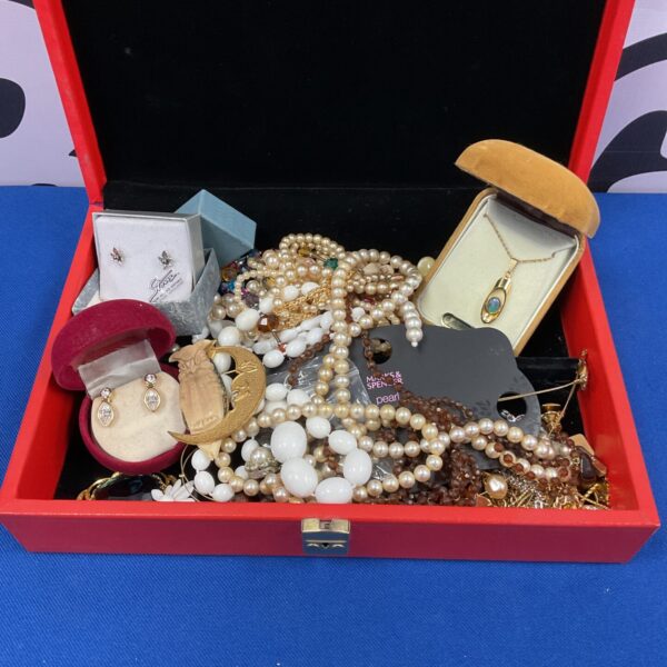Vintage red jewellery box filled with assorted costume jewellery.