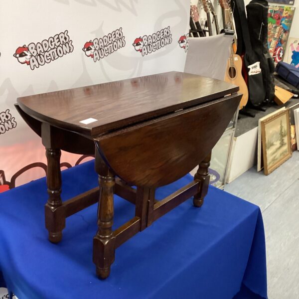 Antique darkwood gate leg table with leaves raised.