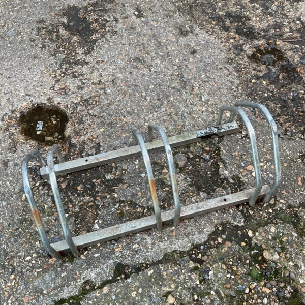 Metal three-bike rack for outdoor bicycle parking.