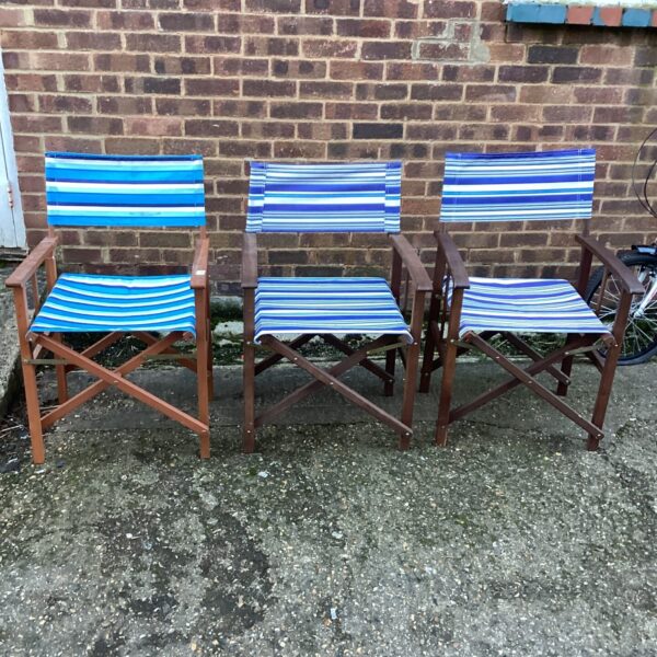 Three vintage folding wooden chairs with striped seats.