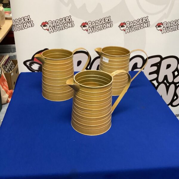 Three vintage metal gold jugs for display or collection.