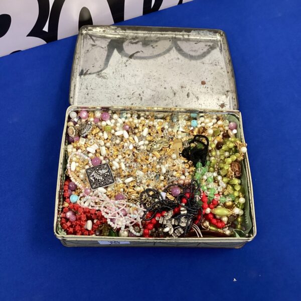Tin filled with colourful vintage costume jewellery beads.
