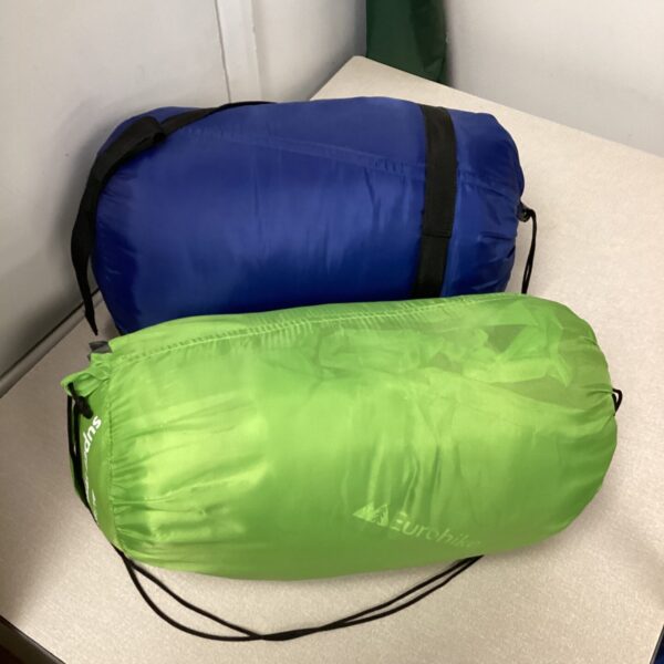 Two compact blue and green sleeping bags for camping and hiking.