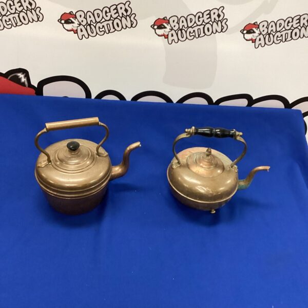 Pair of vintage copper kettles with handles and spouts.
