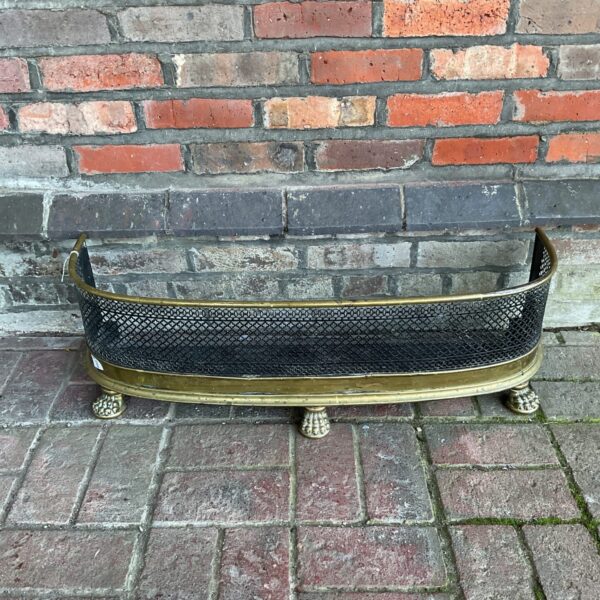 Antique Victorian brass fireplace fender with claw feet.