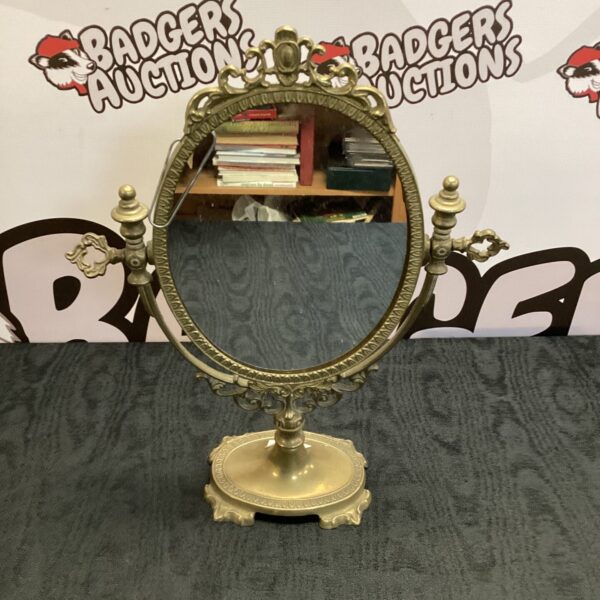 Ornate vintage brass table mirror with oval reflective surface.