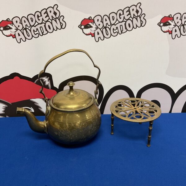 Vintage brass teapot and trivet set on display.