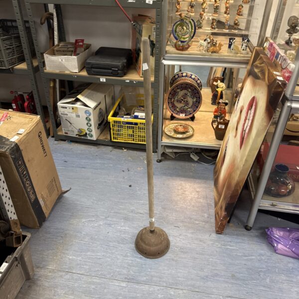 Vintage copper wash dolly with wooden handle, antique laundry tool.