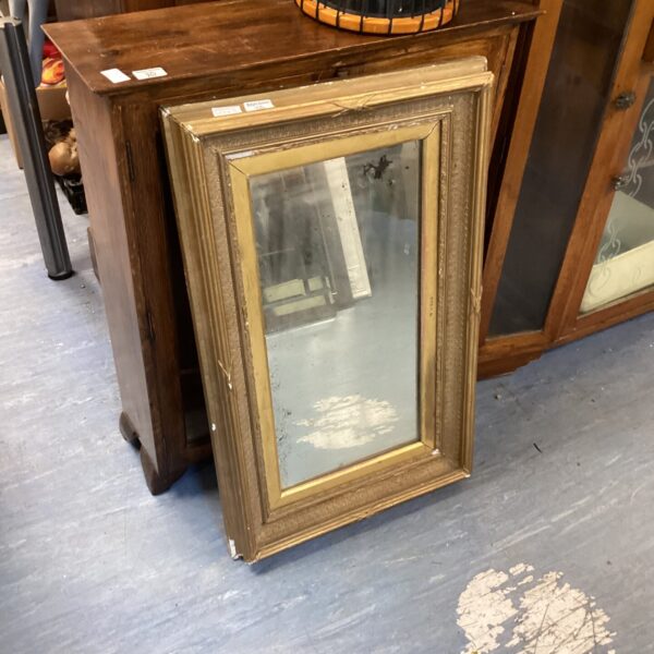 Ornate vintage gilded mirror with detailed frame.