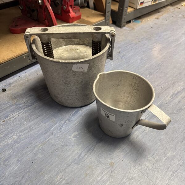 Vintage cast iron meat press jug for collecting rendered fats.