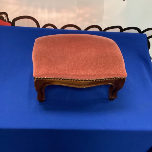 Vintage padded foot stool with wooden legs and textured fabric.