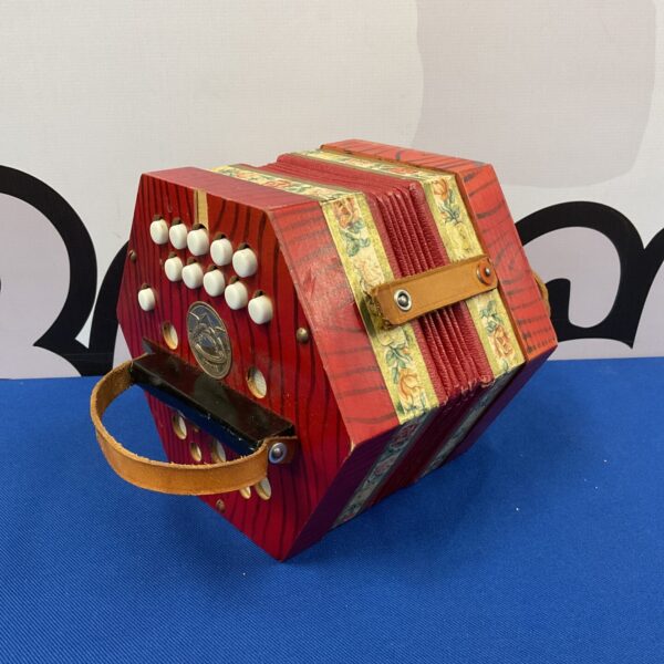 Red vintage Scholer accordion with button keys and decorative panels.