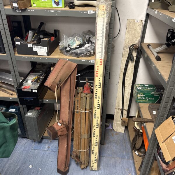 Vintage wooden surveying tripod with measuring scale.