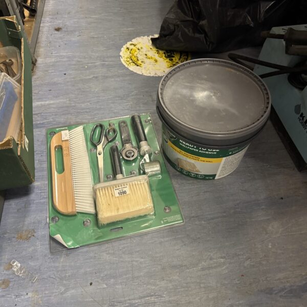 Vintage wallpapering tool kit with adhesive tub for DIY projects.