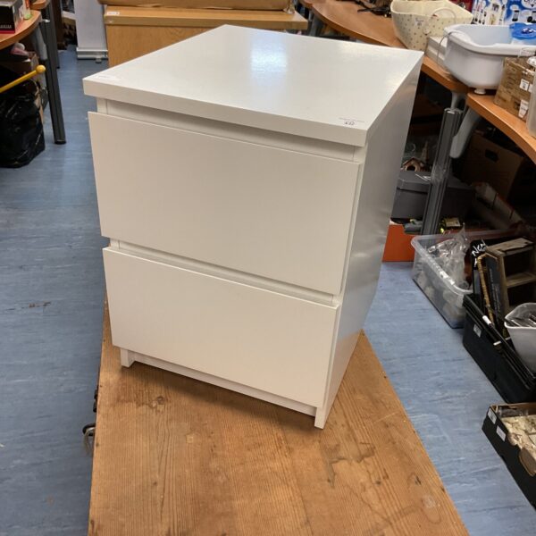 White Ikea bedside table with two drawers for bedroom storage.