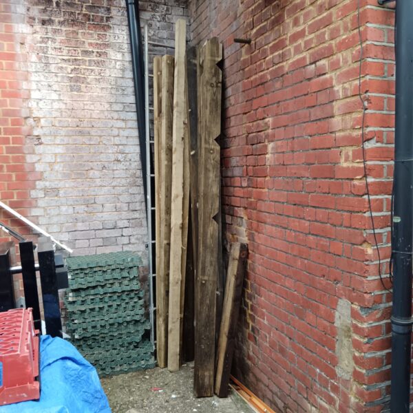 Stack of reclaimed timber planks in a garden setting.