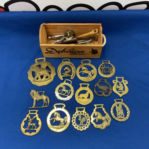 Vintage horse brasses and bottle openers displayed on a wooden surface.