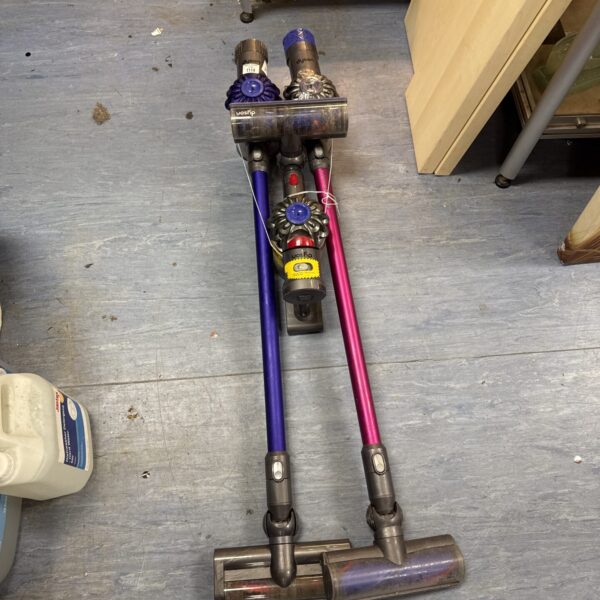 Three Dyson cordless hoovers for spares or repair, colourful cleaning tools.