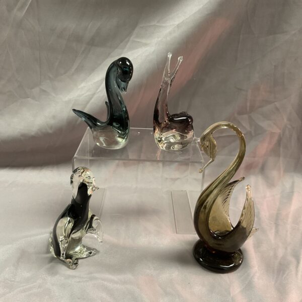 Collection of glass animal figurines including swans, penguin and snail.