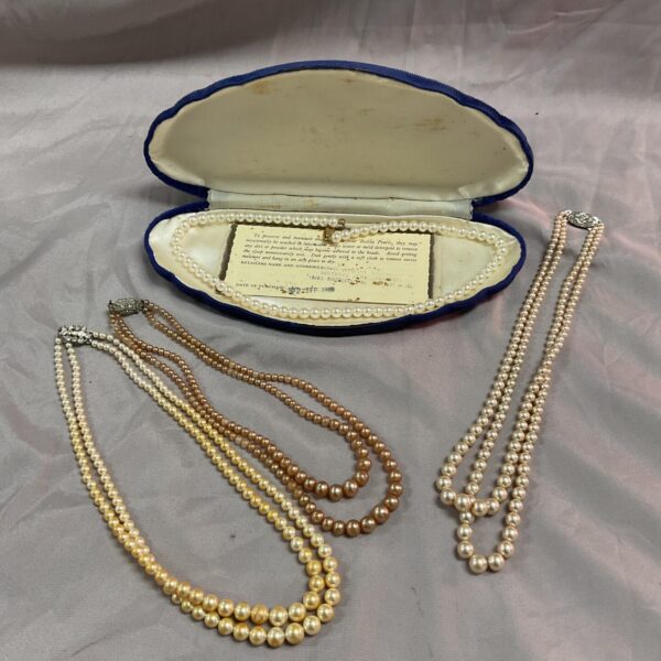 Vintage faux pearl necklaces displayed in a velvet case.
